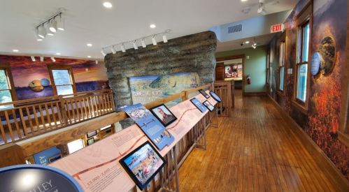 Interior view of a museum exhibit featuring informational displays and scenic murals on the walls.