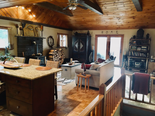 Cozy living room with wooden beams, a stone fireplace, and a mix of rustic and modern decor.