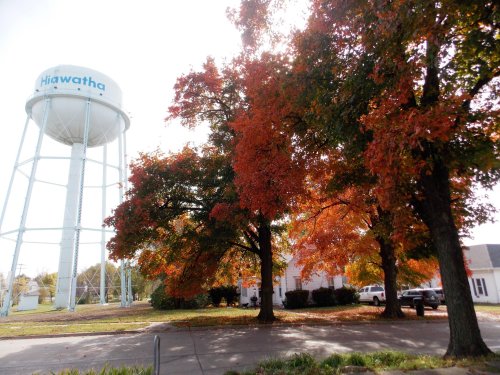 A water tower labeled "Hiawatha" surrounded by vibrant autumn trees with orange and red leaves.