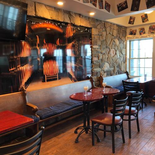 Cozy interior of a restaurant with stone walls, wooden tables, and a large mural of barrels in a cellar.