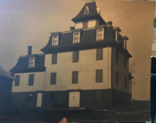 Historic building with a unique roof design, featuring multiple gables and a two-tone exterior.
