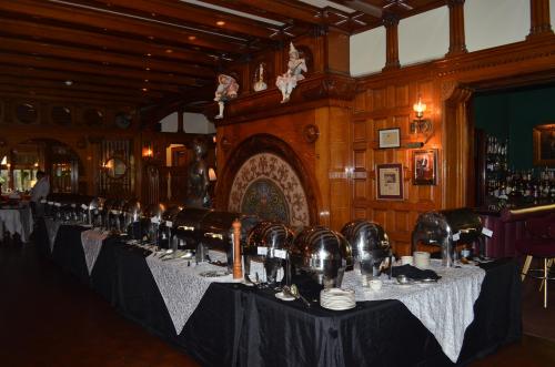 A lavish buffet setup with silver chafing dishes on a table in an elegant wooden dining room.