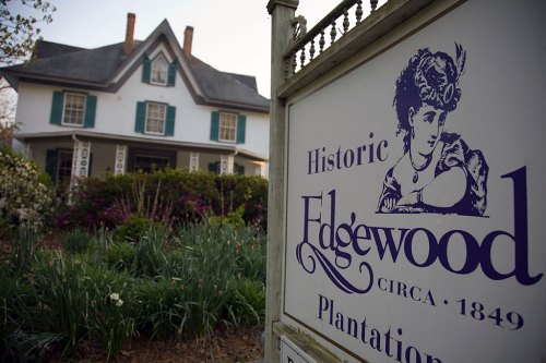 Sign for Edgewood Plantation, established in 1849, with a historic house and blooming flowers in the background.