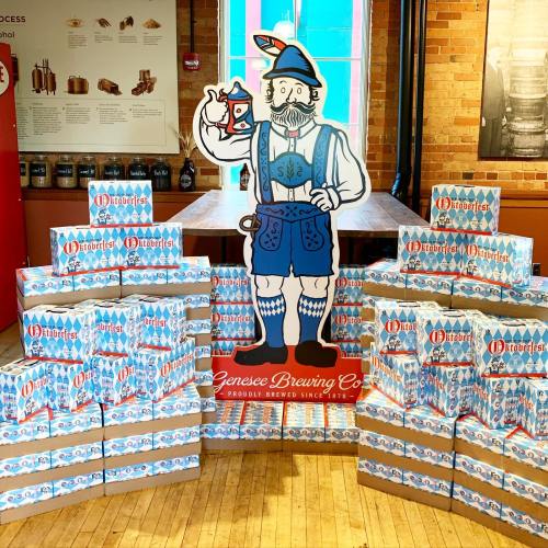 A colorful display featuring a cartoon character holding a lantern, surrounded by stacked beer boxes at a brewery.