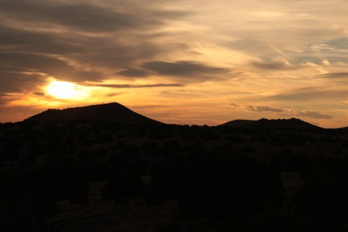 Silhouetted mountains against a colorful sunset sky with clouds.