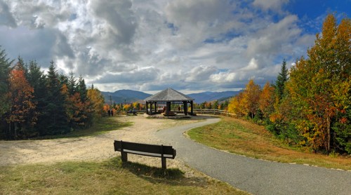 Scenic view of a gazebo surrounded by colorful autumn trees and a winding path under a cloudy sky.