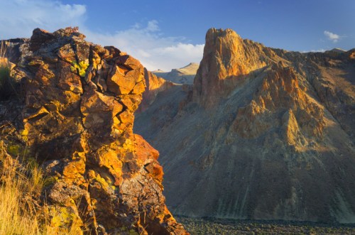 A rugged landscape featuring colorful rock formations and steep mountains under a clear blue sky.