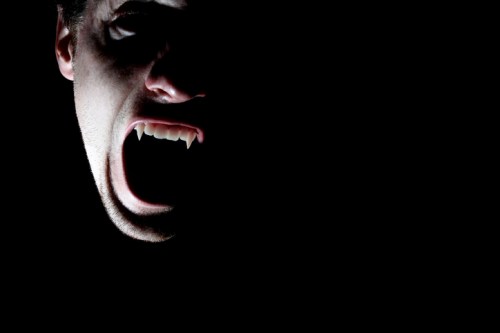 A shadowy figure with fangs, screaming in darkness, creating a dramatic and eerie atmosphere.