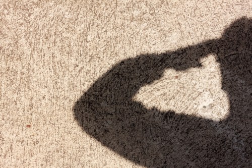 A shadow of a hand making a gesture on a textured surface.
