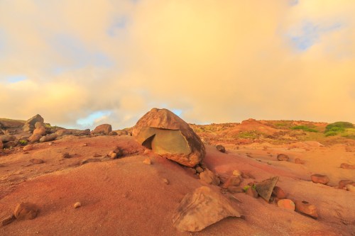A rocky landscape with large boulders under a soft, golden sky at sunset.