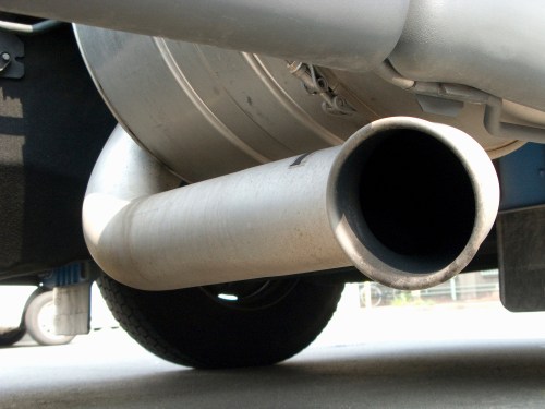 Close-up of a vehicle's exhaust pipe, showing the metallic surface and the opening of the pipe.