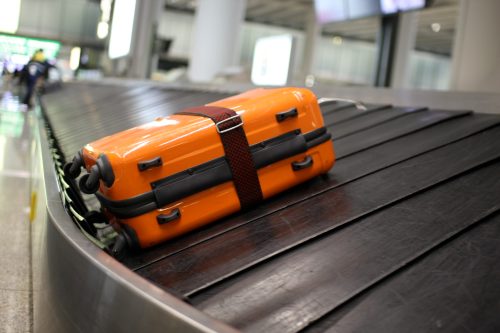An orange suitcase sits on a luggage carousel at an airport.