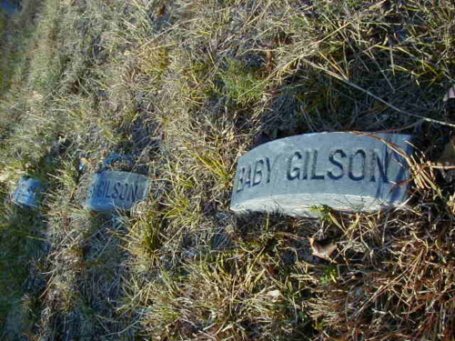 Three gravestones in grass, with the names "Gilson" and "Baby Gilson" visible.