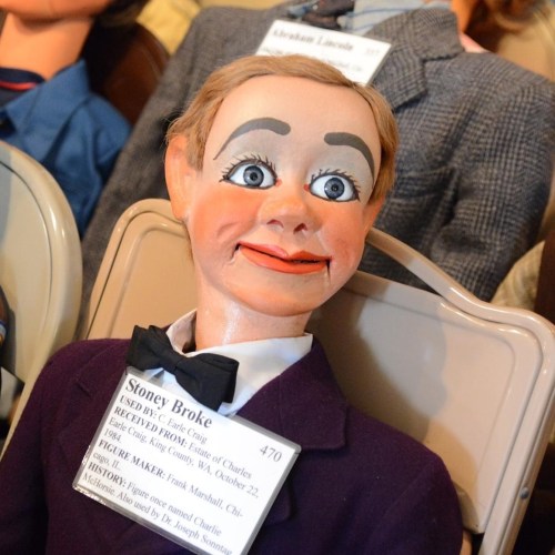 A ventriloquist dummy named Stoney Broke, dressed in a suit with a bow tie, displayed with a name tag.