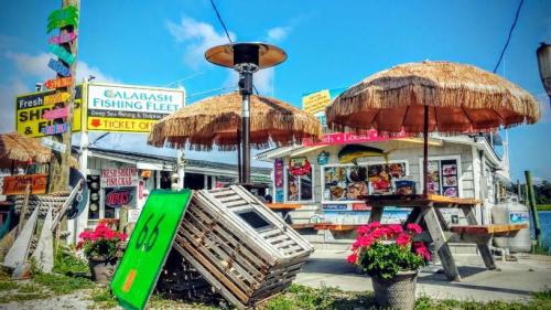 A seaside eatery with thatched umbrellas, colorful signs, and flower pots, inviting visitors to enjoy fresh seafood.