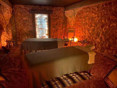 A tranquil spa room with two massage tables, warm lighting, and stone walls, creating a relaxing atmosphere.