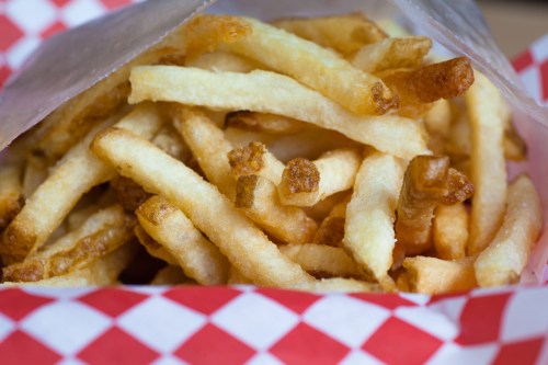 A close-up of golden, crispy French fries in a red and white checkered paper container.
