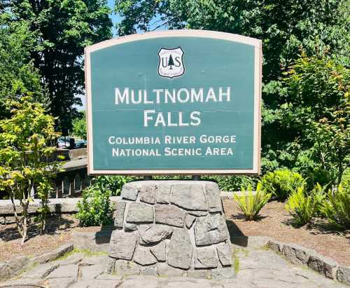 Sign for Multnomah Falls in the Columbia River Gorge National Scenic Area, surrounded by greenery.