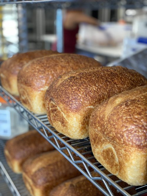 Freshly baked loaves of bread cooling on a wire rack in a bakery.