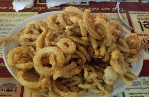 A large plate filled with golden, crispy fried onion rings.