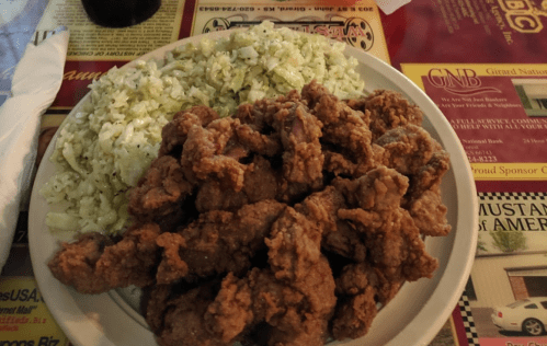 A plate of crispy fried chicken served with a side of shredded cabbage.