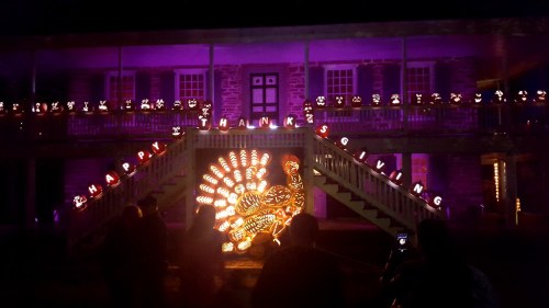 A brightly lit display featuring a turkey and "Happy Thanksgiving" sign in front of a historic building at night.