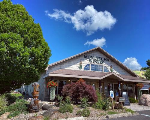 Exterior of Montezuma Winery with a blue sky, fluffy clouds, and colorful flowers in front.