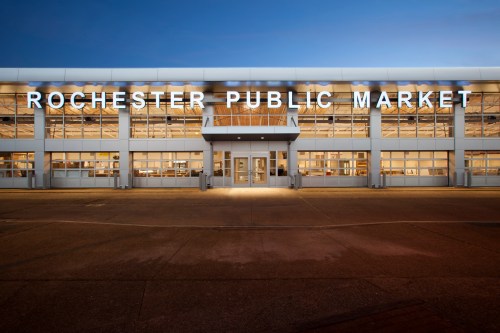 Exterior view of the Rochester Public Market building at dusk, featuring large illuminated signage.