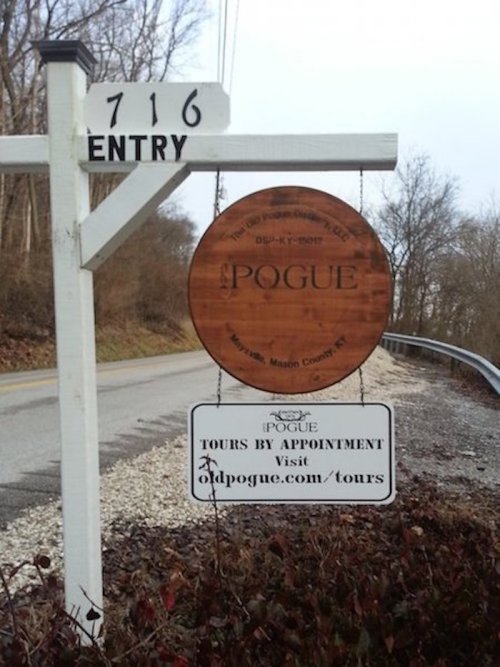 Signpost for Pogue tours, featuring a wooden circular sign and details for appointments and website.