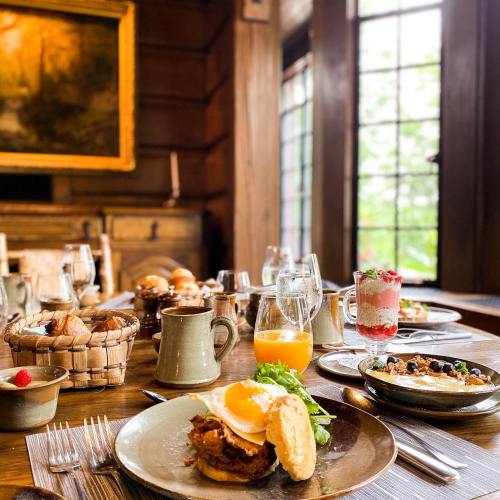 A beautifully set dining table with a variety of breakfast dishes, including eggs, pastries, and drinks, in a cozy room.