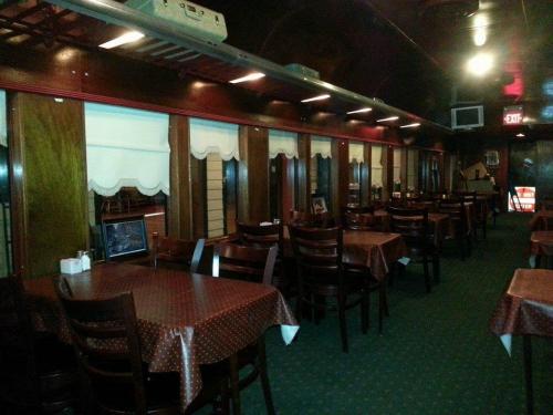Interior of a restaurant featuring wooden decor, tables with red tablecloths, and window coverings.
