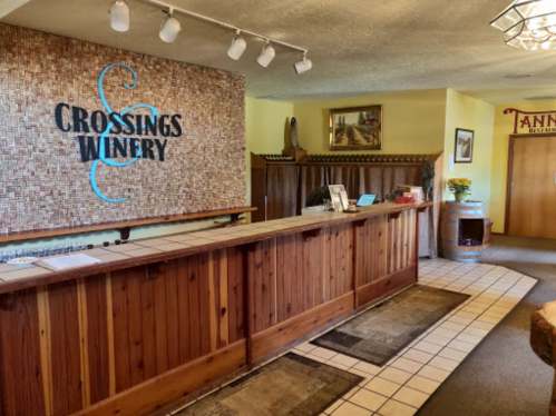 Interior of Crossings Winery featuring a wooden reception desk, decorative wall, and warm lighting.