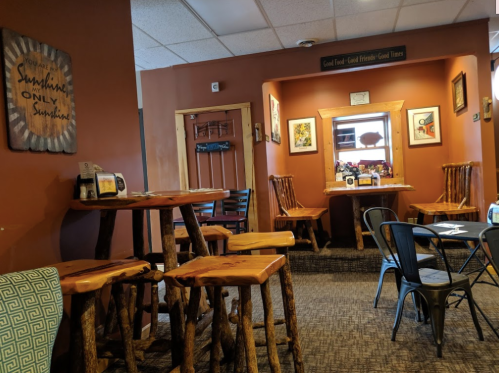 Cozy café interior with wooden tables, rustic decor, and warm orange walls, creating a welcoming atmosphere.