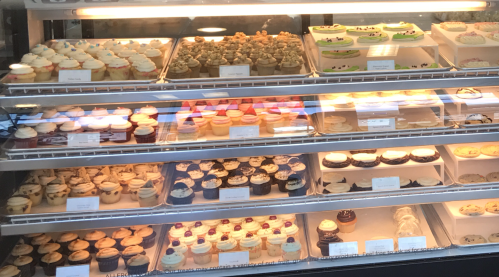 A display case filled with a variety of colorful cupcakes and desserts, showcasing different flavors and decorations.