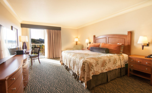A cozy hotel room featuring a large bed, wooden furniture, and a window with natural light.