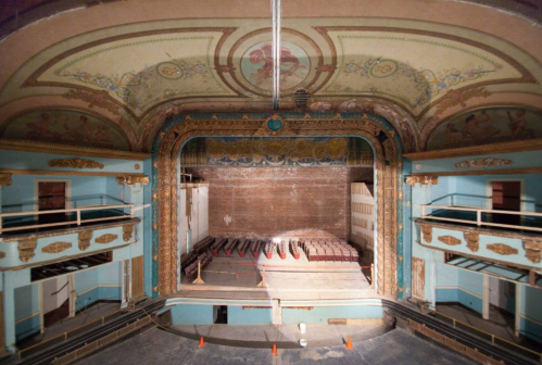 Interior view of a vintage theater, showcasing ornate ceilings and empty seating, with a stage in the background.