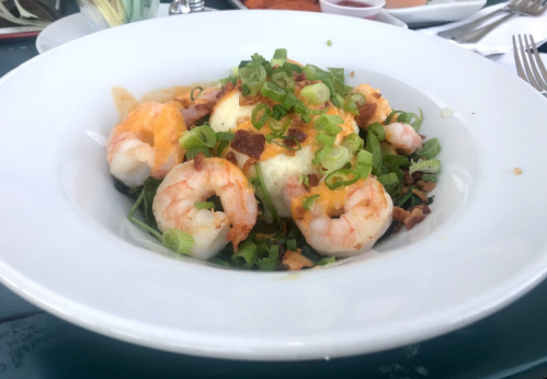 A bowl of shrimp topped with green onions and bacon, served over a bed of creamy mashed potatoes.