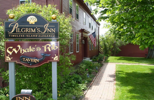 Sign for Pilgrim's Inn and Whale's Rib Tavern, with a brick path and greenery in a charming outdoor setting.