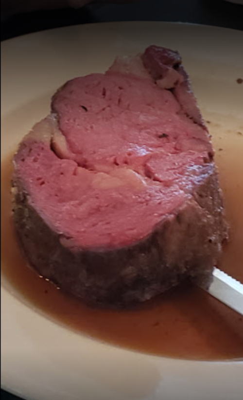 A slice of medium-rare roast beef on a plate, with a rich brown sauce surrounding it.