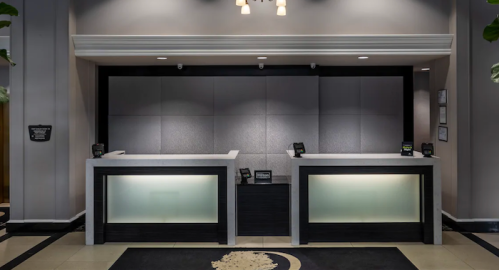 Modern hotel reception area with two sleek desks and a minimalist design, featuring soft lighting and a neutral color palette.