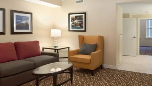 Cozy hotel room featuring a sofa, armchair, coffee table, and framed artwork on the walls.