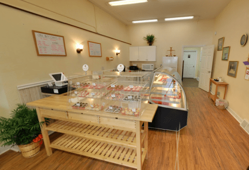 A cozy dessert shop interior featuring display cases of sweets, wooden tables, and warm lighting.