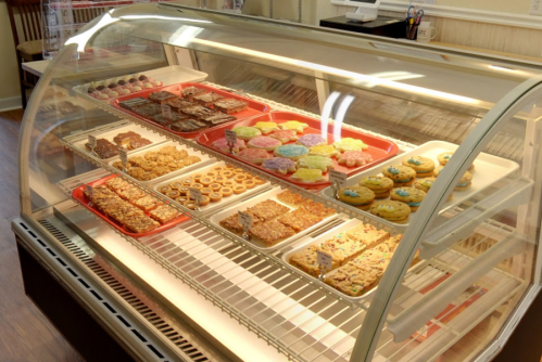 A display case filled with various baked goods, including cookies, brownies, and colorful frosted treats.