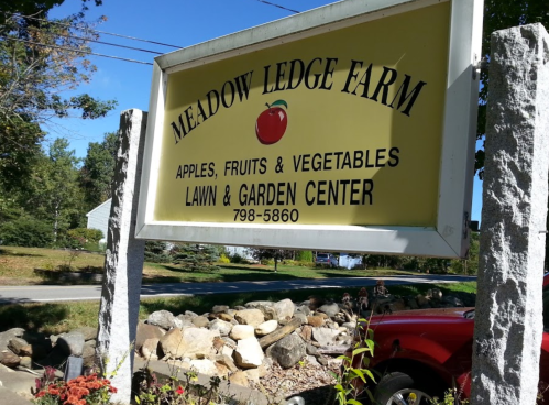 Sign for Meadow Ledge Farm, advertising apples, fruits, vegetables, and a lawn and garden center. Phone number included.