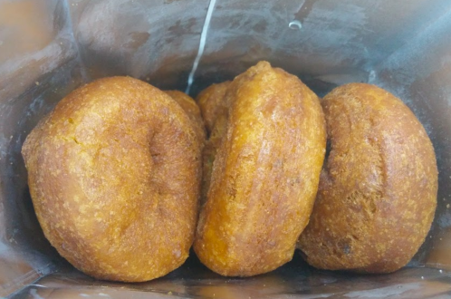 Three golden-brown donuts stacked inside a silver bag, with a slightly shiny surface.