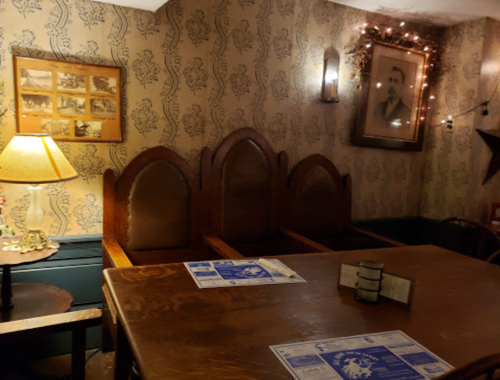 Cozy restaurant interior with wooden chairs, a table, vintage photos, and soft lighting.