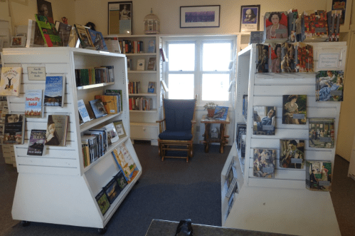 A cozy library interior with two book displays, a rocking chair, and shelves filled with books and magazines.