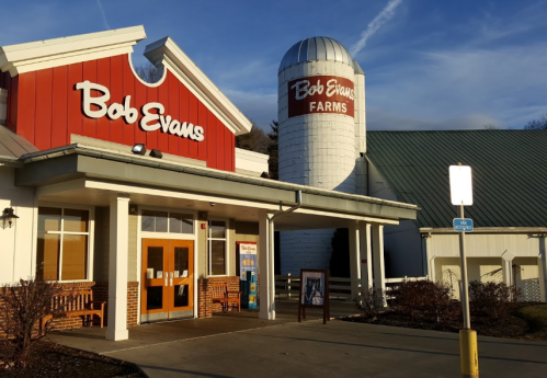 Exterior of a Bob Evans restaurant featuring a red and white building and a silo labeled "Bob Evans Farms."