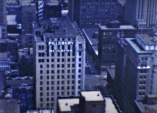 Aerial view of a cityscape featuring the Pillsbury Building and surrounding urban architecture.