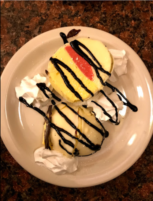 A plate with two scoops of ice cream drizzled with chocolate sauce and topped with whipped cream.
